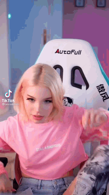 a girl is sitting in a chair wearing a pink shirt that says `` still a babygirl '' .