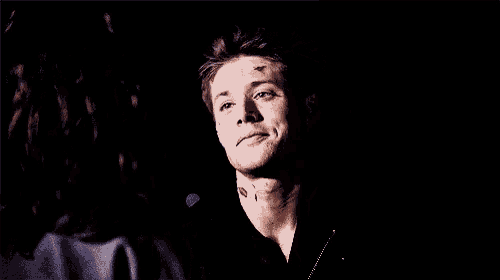 a man with a tattoo on his neck smiles at a woman