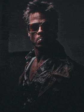 a man wearing sunglasses and a leather jacket is laughing
