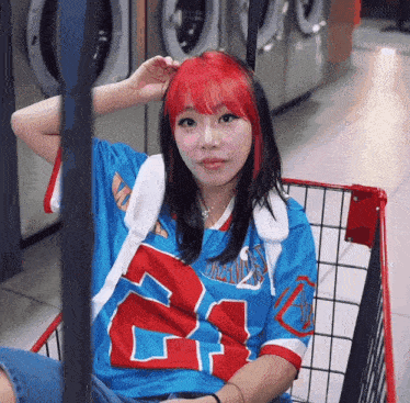 a woman wearing a jersey with the number 24 on it sits in a laundromat cart