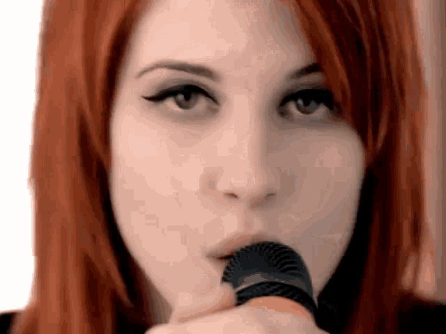 a close up of a woman holding a microphone in her mouth .