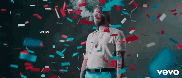 a man is standing in front of a wall of confetti and smoke coming out of his mouth .