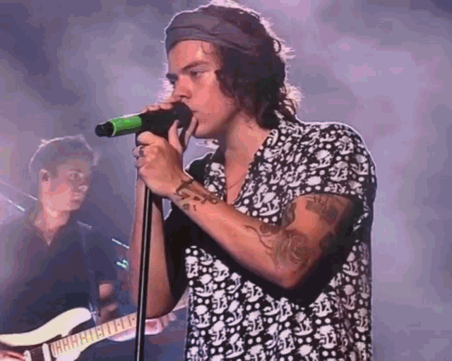 a man singing into a microphone with a band behind him