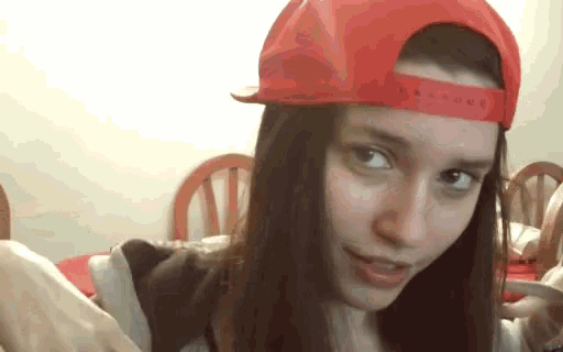 a girl wearing a red baseball cap looks at the camera