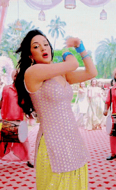 a woman in a purple top and yellow skirt dancing