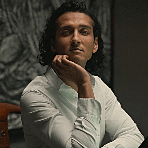 a man in a white shirt has his hand on his face