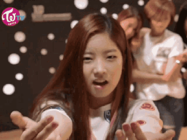 a girl with long red hair is making a funny face with a twice logo in the background