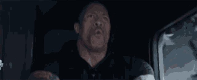 a man is driving a car with his mouth open .