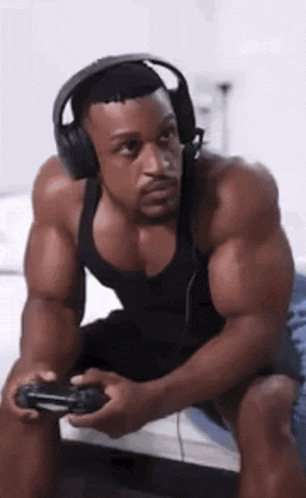 a muscular man wearing headphones is holding a video game controller