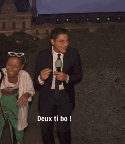 a man in a suit and tie holds a microphone and says ba moin en ti bo !