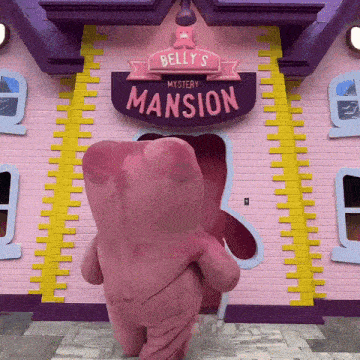 a pink teddy bear is standing in front of belly 's mystery mansion sign