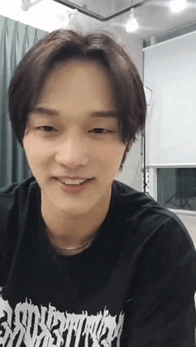 a young man wearing a black shirt with the word eternity on it is smiling
