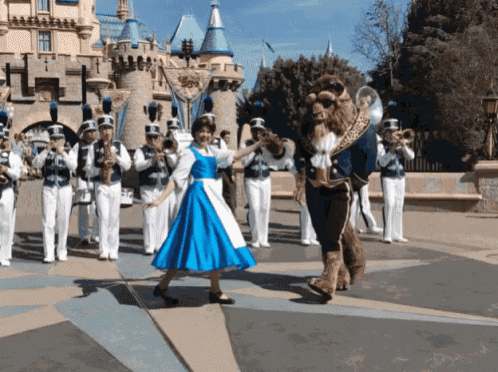 a woman in a blue dress is dancing with a mascot