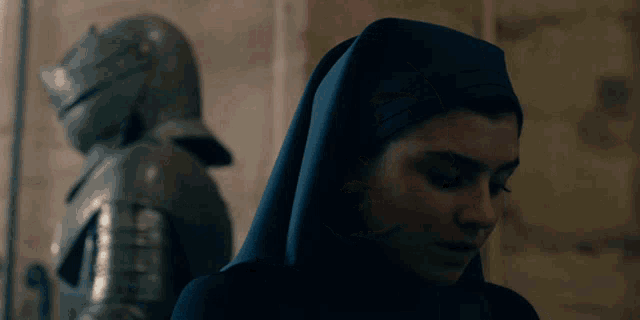 a woman in a nun 's robe stands in front of a knight in armor