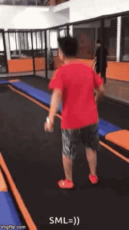 a man in a red shirt is jumping on a trampoline with the caption sml = ) .