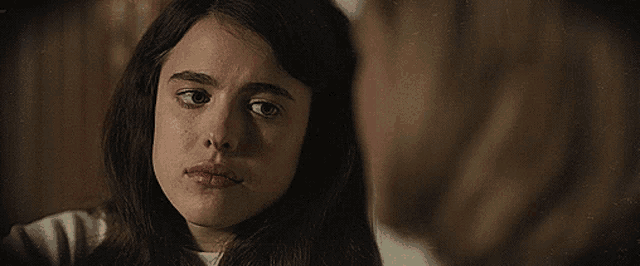 a close up of a girl 's face with a woman 's face in the background
