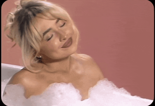 a woman is taking a bath with bubbles on her chest