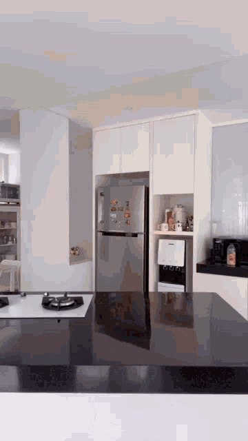 a kitchen with a stainless steel refrigerator and a water dispenser on the counter