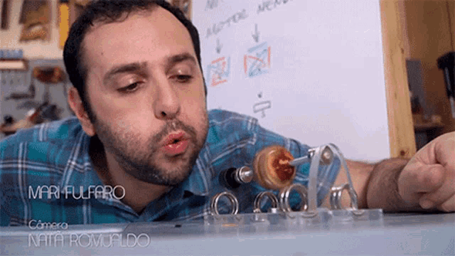 a man blowing a kiss in front of a white board with the name mari fulfaro written on it