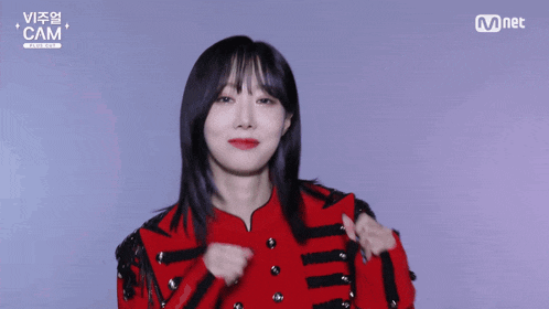 a woman in a red jacket stands in front of a screen that says mnet