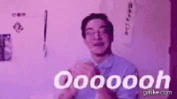 a man in a blue shirt and glasses is making a funny face with his hands in the air .