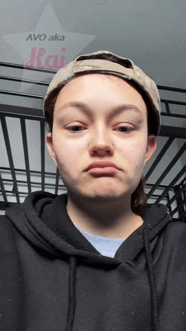 a woman wearing a hat and a black hoodie is making a face