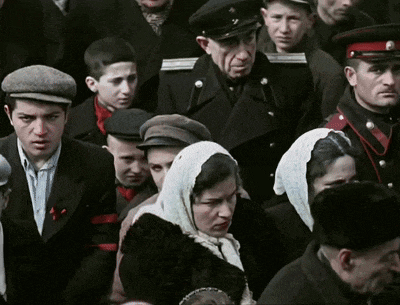 a crowd of people including a woman wearing a scarf and a man wearing a hat