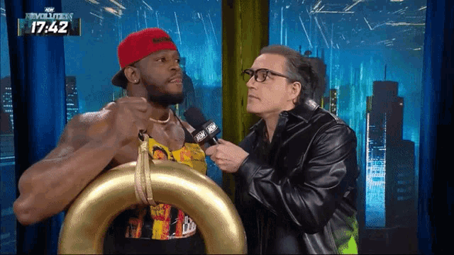 a man in a red hat is being interviewed by a man in a black jacket on a tv show called evolution