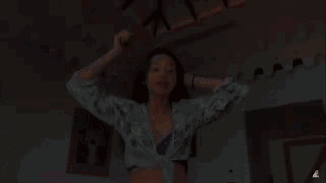 a woman in a bikini is brushing her hair in a room