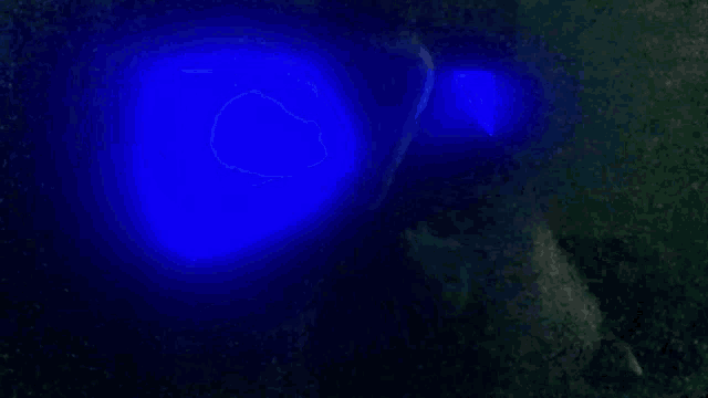 a person wearing glow in the dark glasses with a blue light coming out of them .