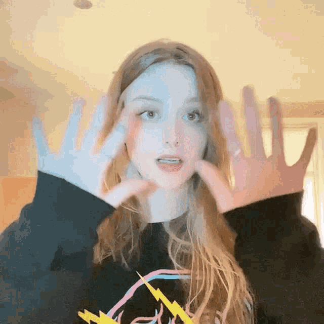 a woman wearing a black sweatshirt with a lightning bolt on it shows off her hands