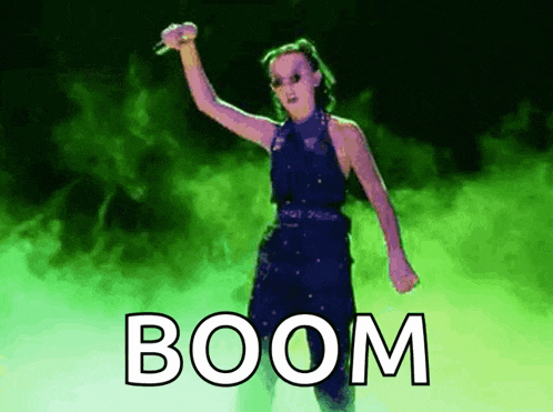a woman in a blue dress is holding a microphone and the word boom is on the screen