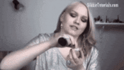 a woman is applying makeup to her face .