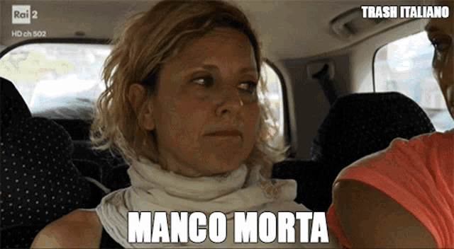 a woman wearing a scarf around her neck is sitting in a car with trash italiano written above her