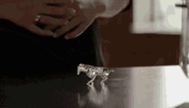 a statue of a horse is on a table with a person behind it