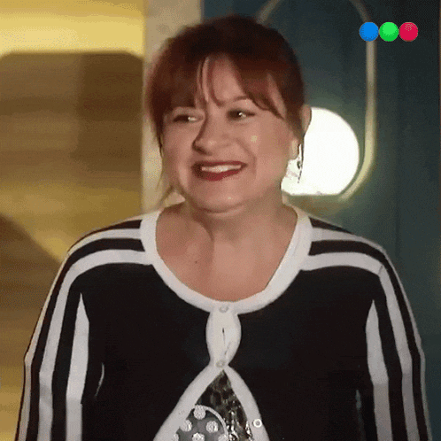 a woman with red hair is smiling and wearing a black and white striped sweater