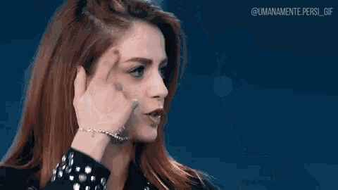 a woman with red hair is making a gesture with her hand and says non mi ricordo niente .