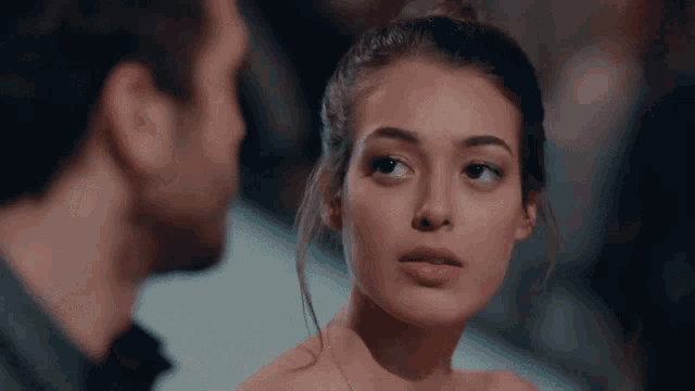 a man and a woman are looking at each other and the woman is wearing a necklace