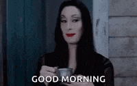 a woman in a black dress is holding a cup of coffee and says `` good morning '' .