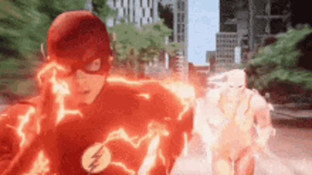 a man in a flash suit is running down a street while another man in a white suit is behind him .