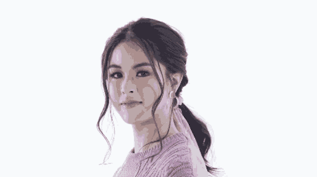 a woman in a pink sweater is winking at the camera .