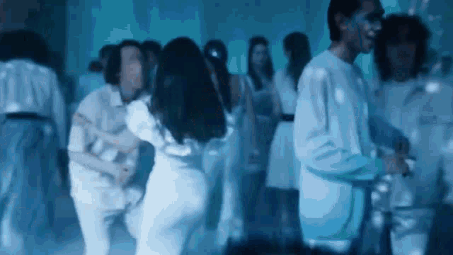 a group of people are dancing together in a dark room .
