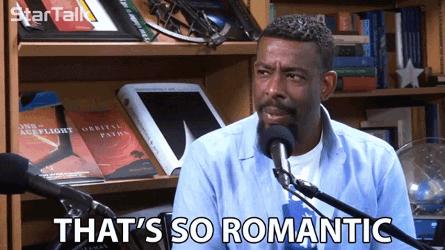 a man talking into a microphone with the words that 's so romantic behind him