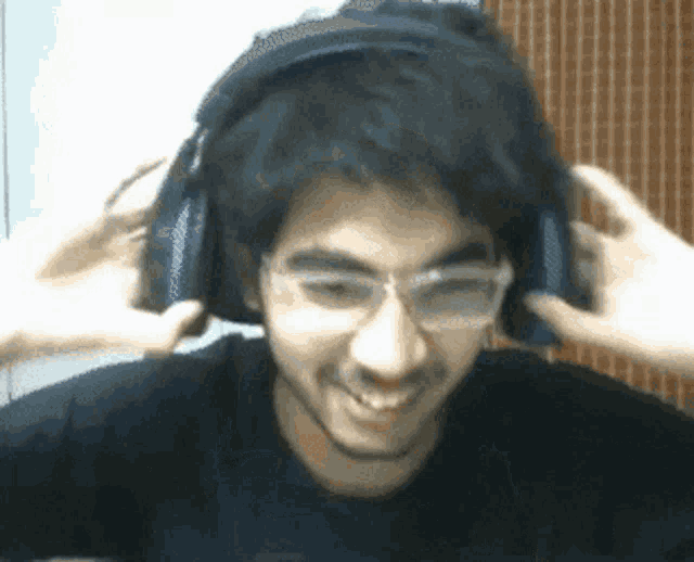 a man wearing headphones and glasses is smiling and making a funny face