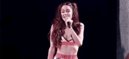a woman is singing into a microphone on a stage while dancing .