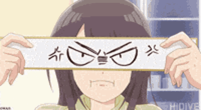 a girl in a green shirt is holding a piece of paper over her face .