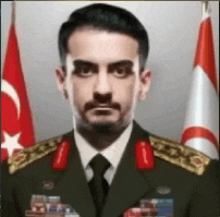 a man in a military uniform is standing in front of a flag .