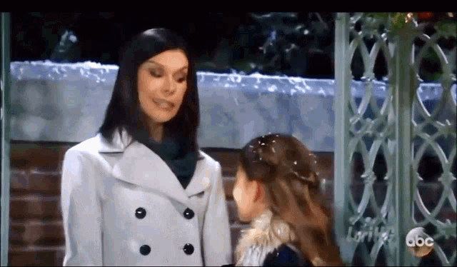 a woman in a white coat is talking to a little girl in a black sweater .