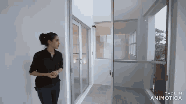 a woman in a black shirt is standing in a room with the words made in animotica on the bottom