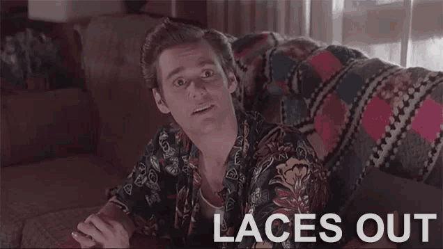 a man is sitting on a couch with the words `` laces out '' written on the screen .